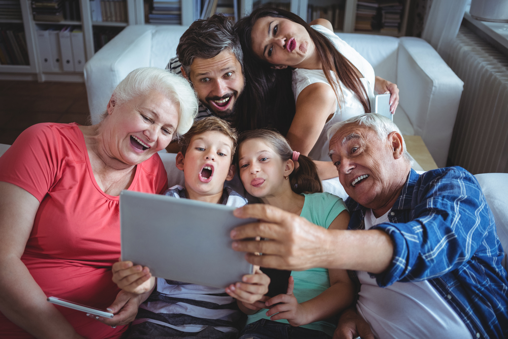 Multi-generation family taking a selfie on digital tablet in living room at home-1
